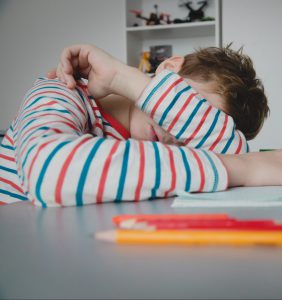 Ein Kind ist müde vom Hausaufgaben machen und auf dem Aufgabenheft eingeschlafen.
