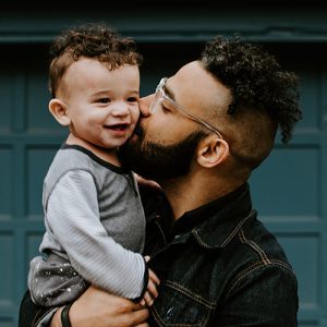 Vater küsst seinen kleines lachendes Kind auf die Wange